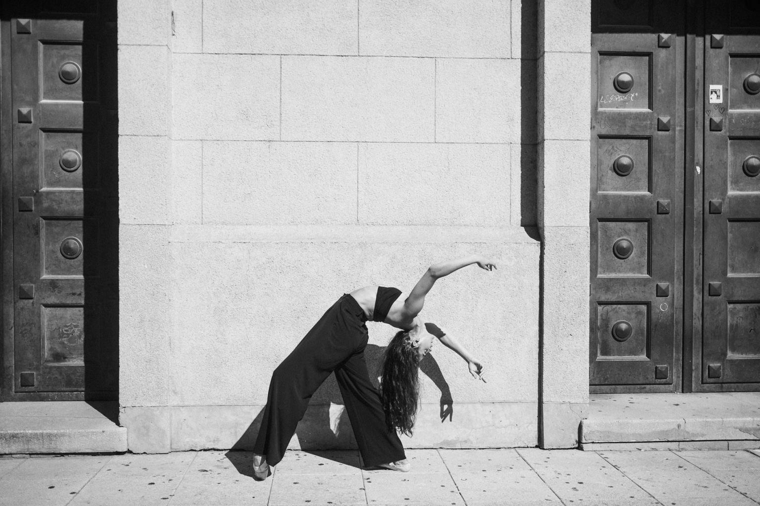 Black and white dancer pose against city wall